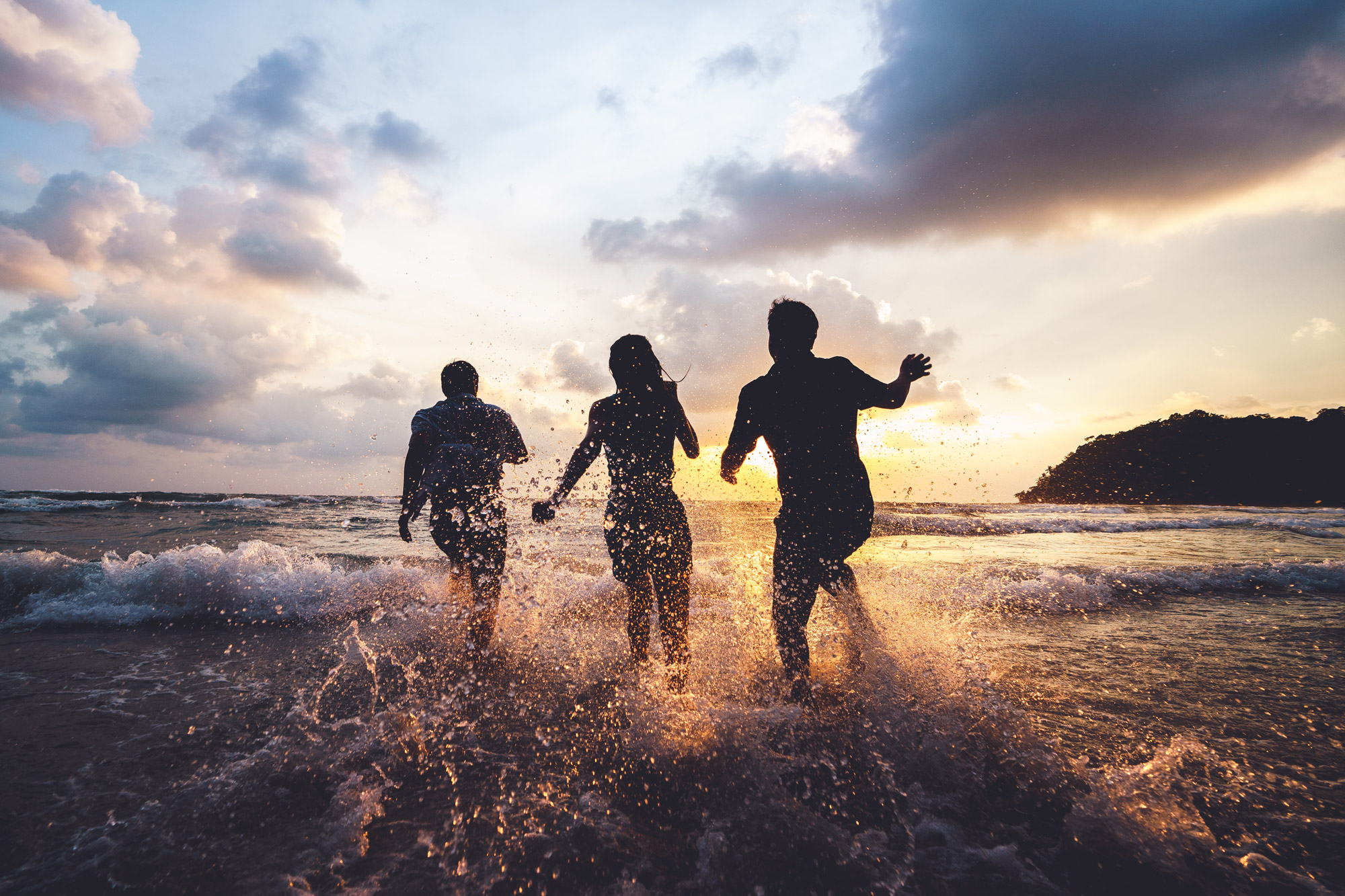 Tre personer springer på stranden